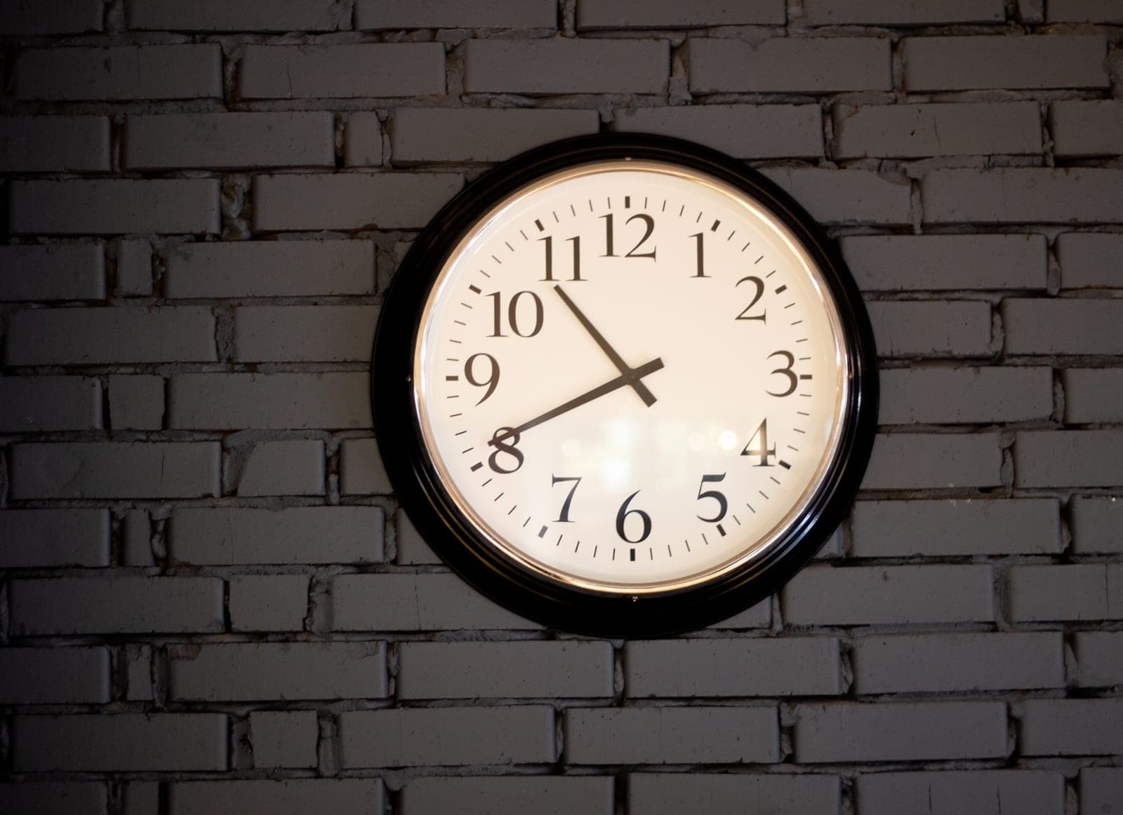 A large analog wall clock mounted on a brick wall, symbolizing a regular care routine.