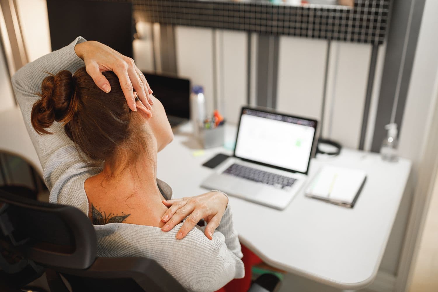 A person performing a chin-tuck neck exercise at a desk, part of a daily routine to reverse tech neck and forward-head posture.